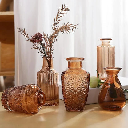 Five Amber Vases on a wooden table next to a book