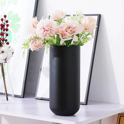 Black Cylinder Vase with pink flowers inside on a white table