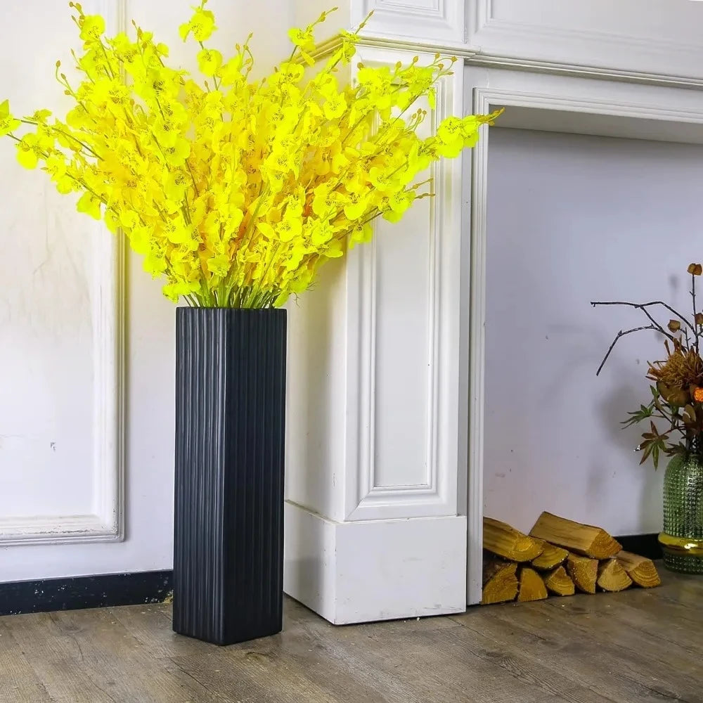 Black Floor Vase with yellow flowers inside next to a wall