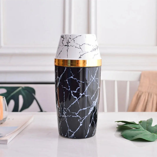 Black Marble Vase with green leafes laying on a white table