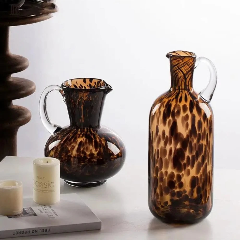 Two Black and Brown Vases next to candles on a white surface