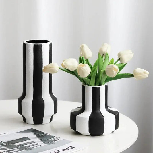 Two Black and White Vases on a white table with white tulips inside