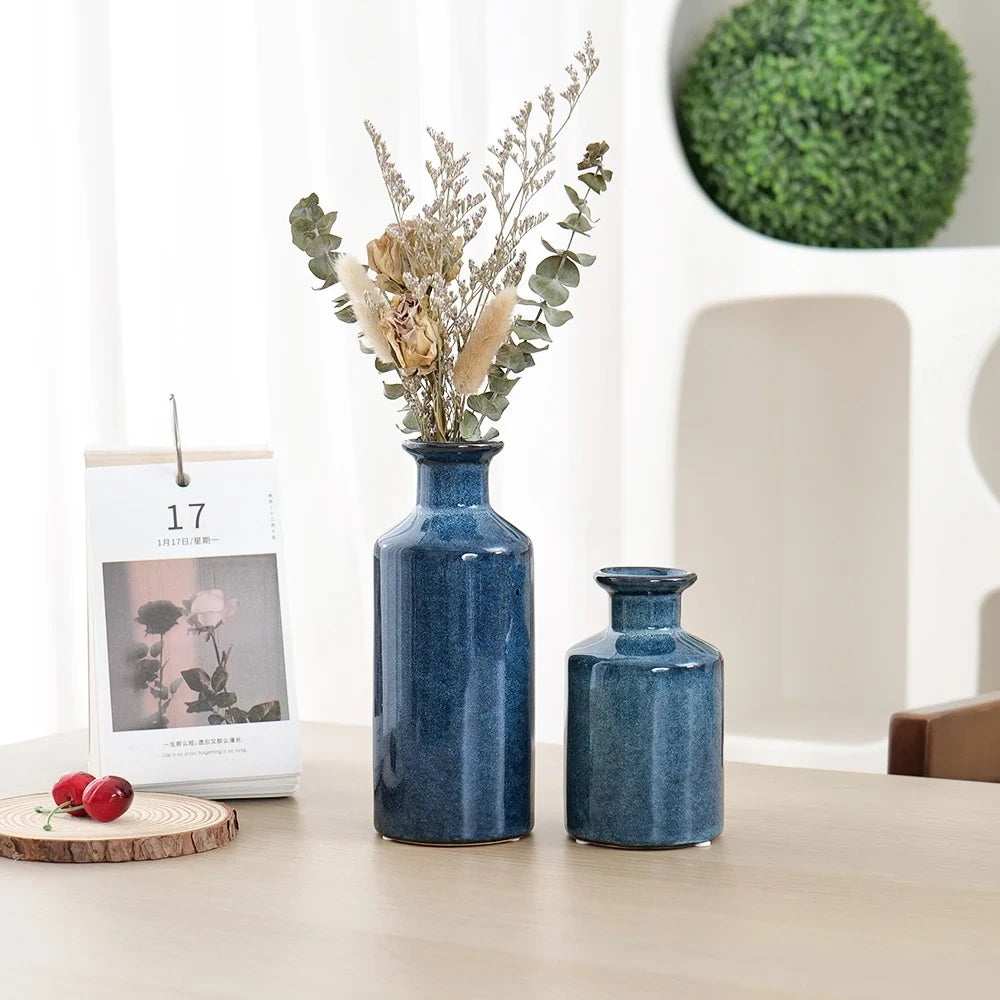 Blue Bud Vase on a beige table with greenery in the background