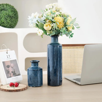 Blue Bud Vases next to a laptop on a beige table with greenery in the background