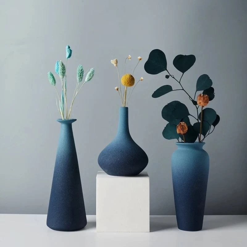 Three Blue Ceramic Vase on a white square with flowers inside