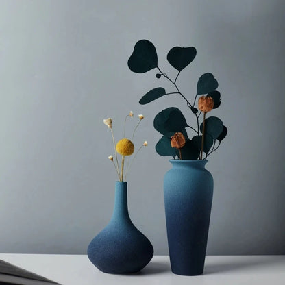 Two Blue Ceramic Vase on a white surface with flowers inside