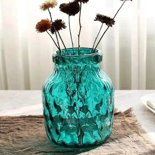 Blue Glass Vase on a brown blanket with white curtains in the background 