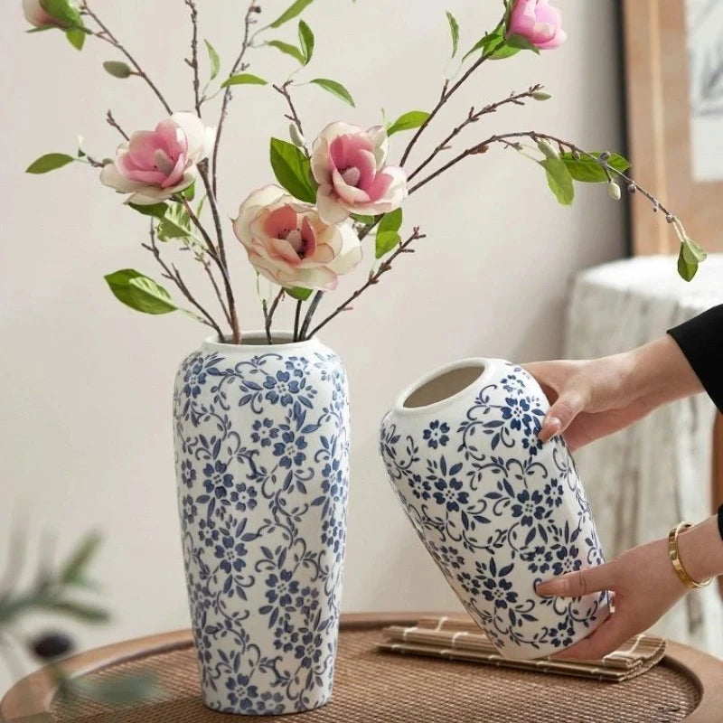 Person holding a Blue White Vase next to another one on a brown table