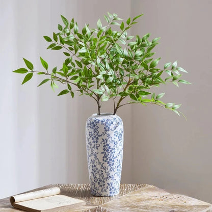 Large Blue White Vase with greenery inside on a beige table