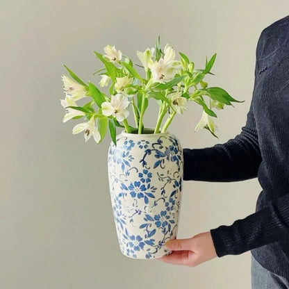 Person holding a Blue White Vase with white flowers inside