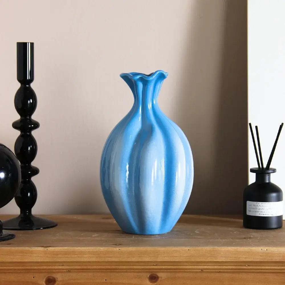 Blue and White Vase on a wooden shelf next to black decorative elements