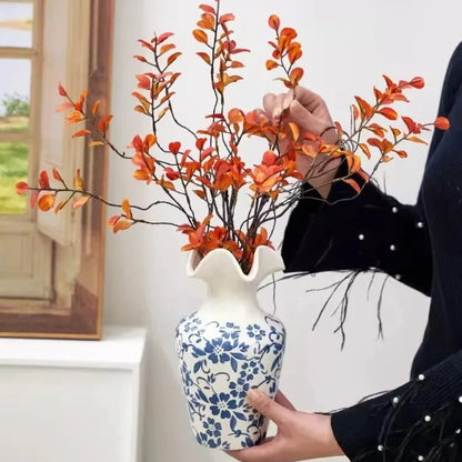 Person holding a Blue and White Vase with plants inside