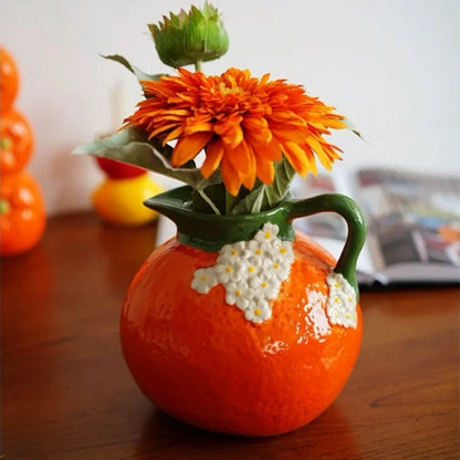 Bright Orange Vase on a wooden desk with orange flowers inside