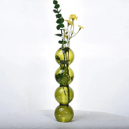 Olive green Bubble Bud Vase with flowers inside on a gray surface