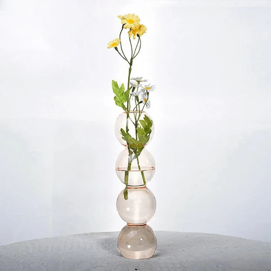 Clear Bubble Bud Vase with flowers inside on a gray surface