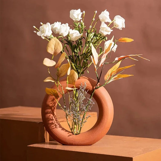 Ceramic Orange Vase with flowers inside on a brown surface