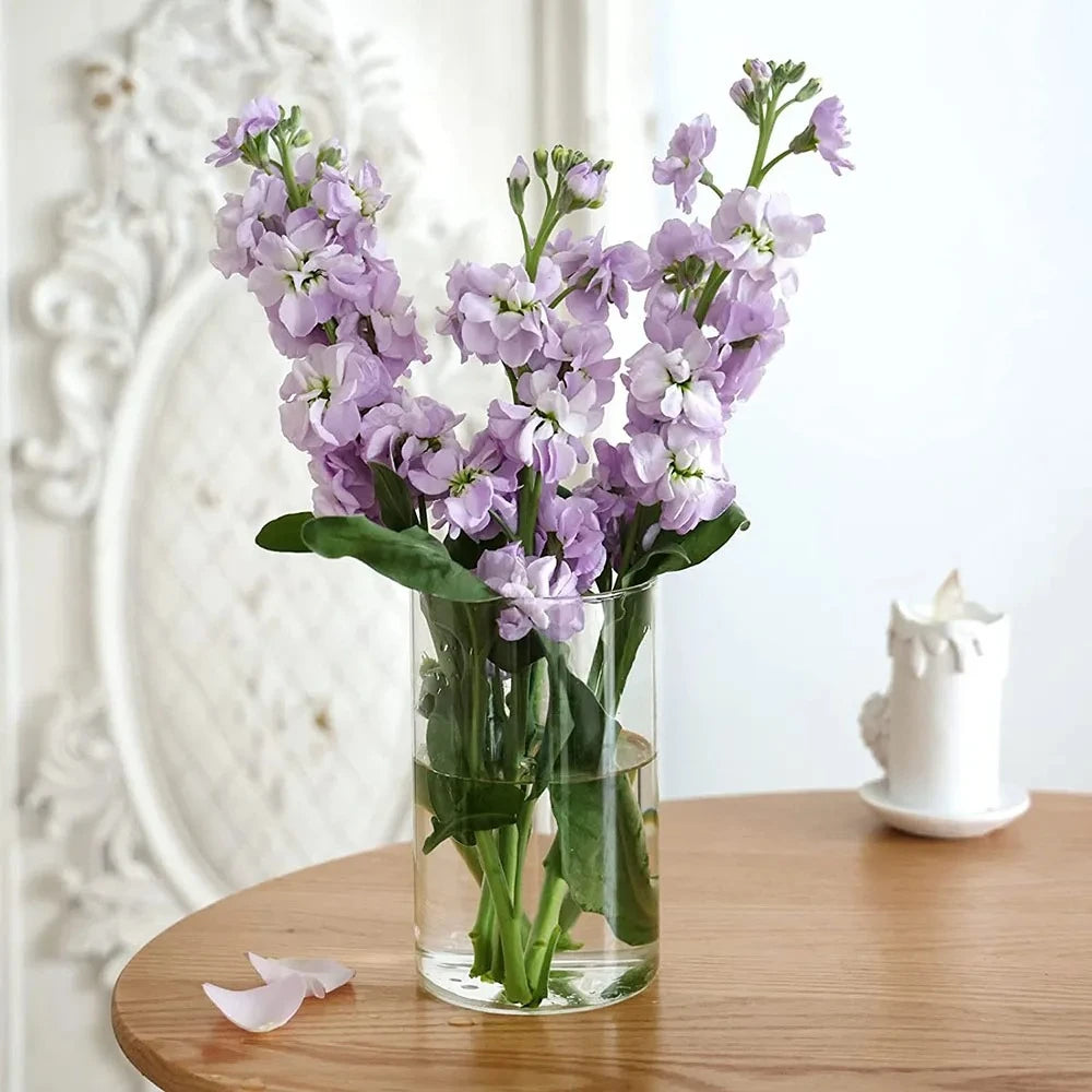 Crystal Cylinder Vase on a wooden table with purple flowers inside