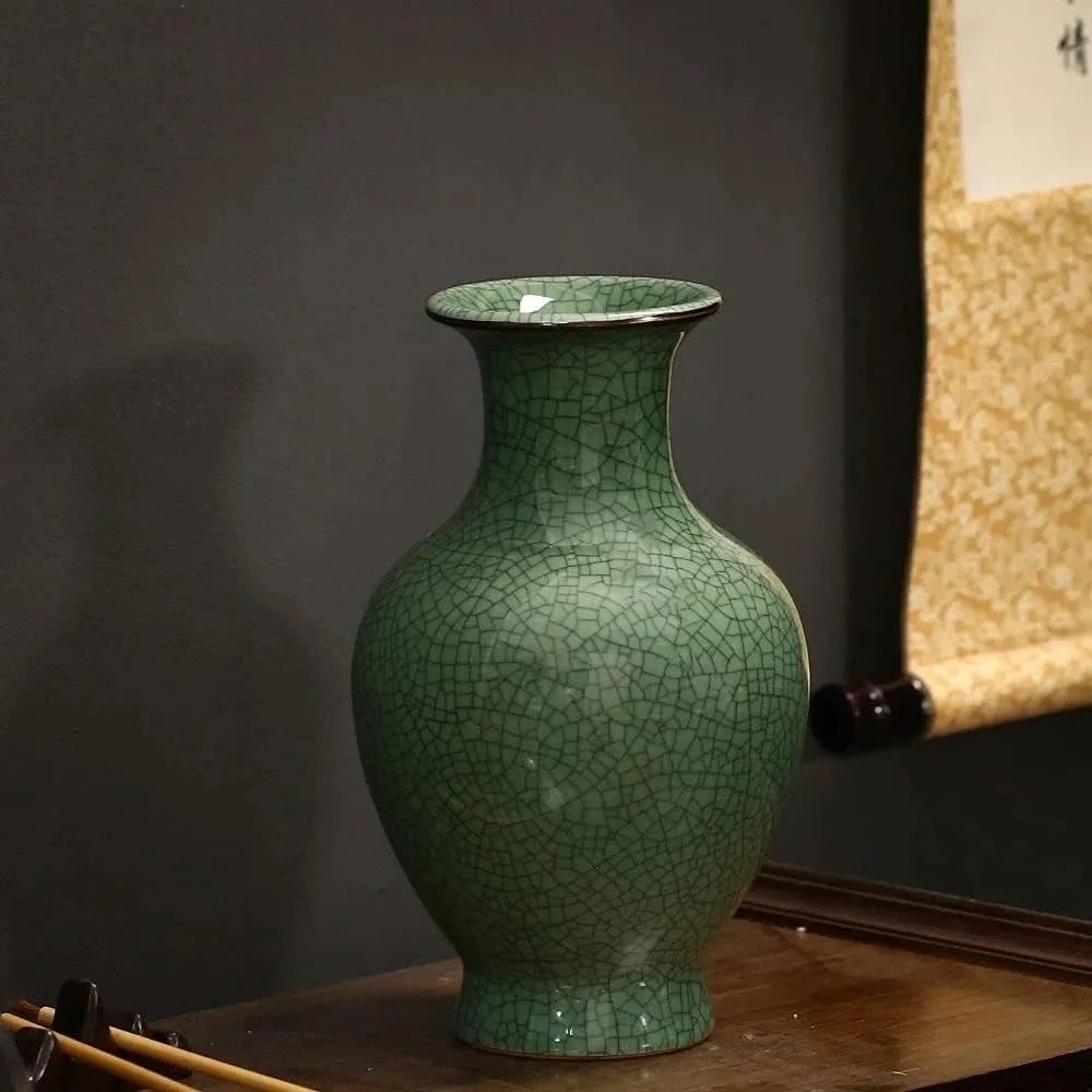 Dark Green Vase on a brown table in front of a gray walll