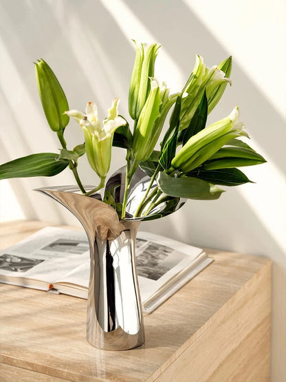 Flower Metal Vase on a wooden shelf with green flowers inside