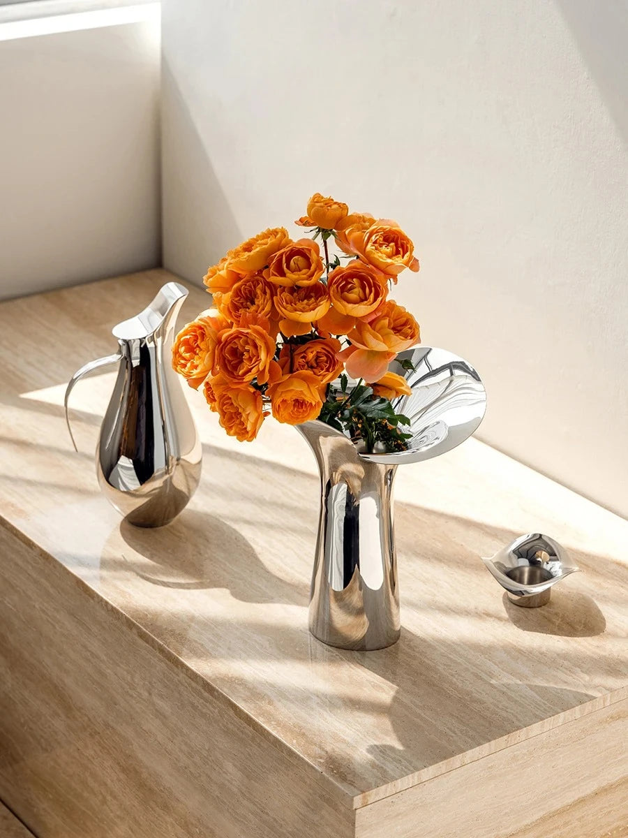 Flower Metal Vase on a wooden shelf with orange flowers inside