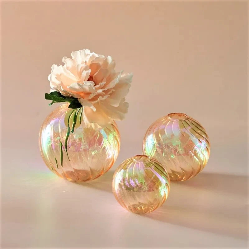 Orange Glass Round Vases with flowers inside on a peach surface