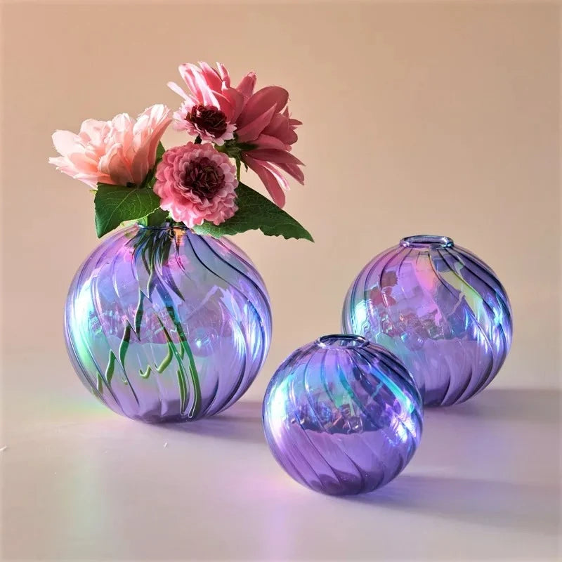 Purple Glass Round Vases with flowers inside on a peach surface