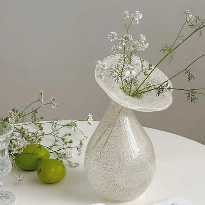 Glass White Vase with greenery inside next to two green apples