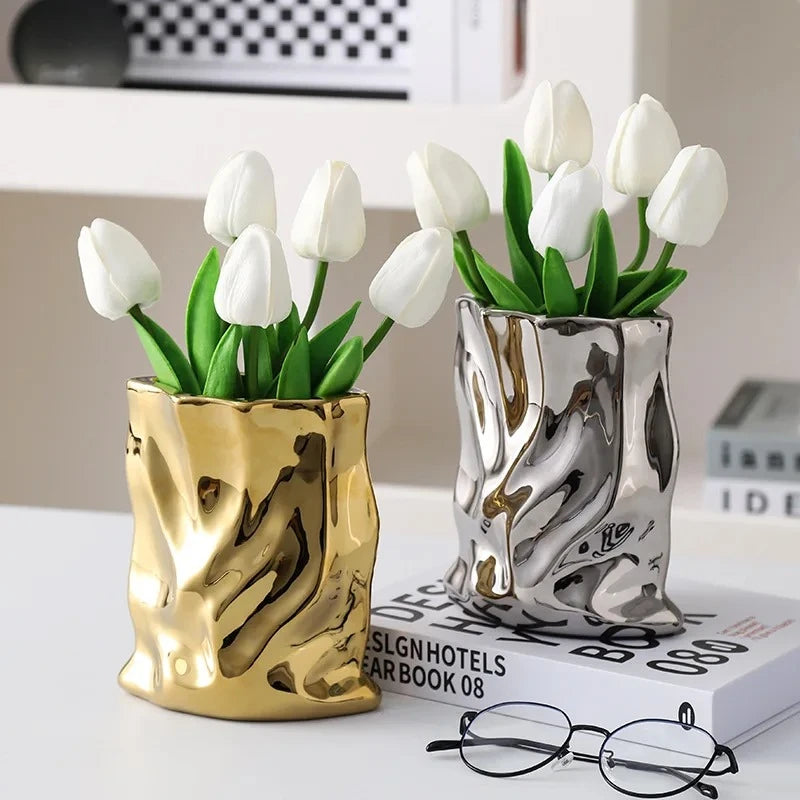 Gold and Silver Vases on a white surface next to a book