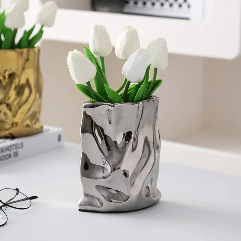 Silver vase with white tulips on a white surface