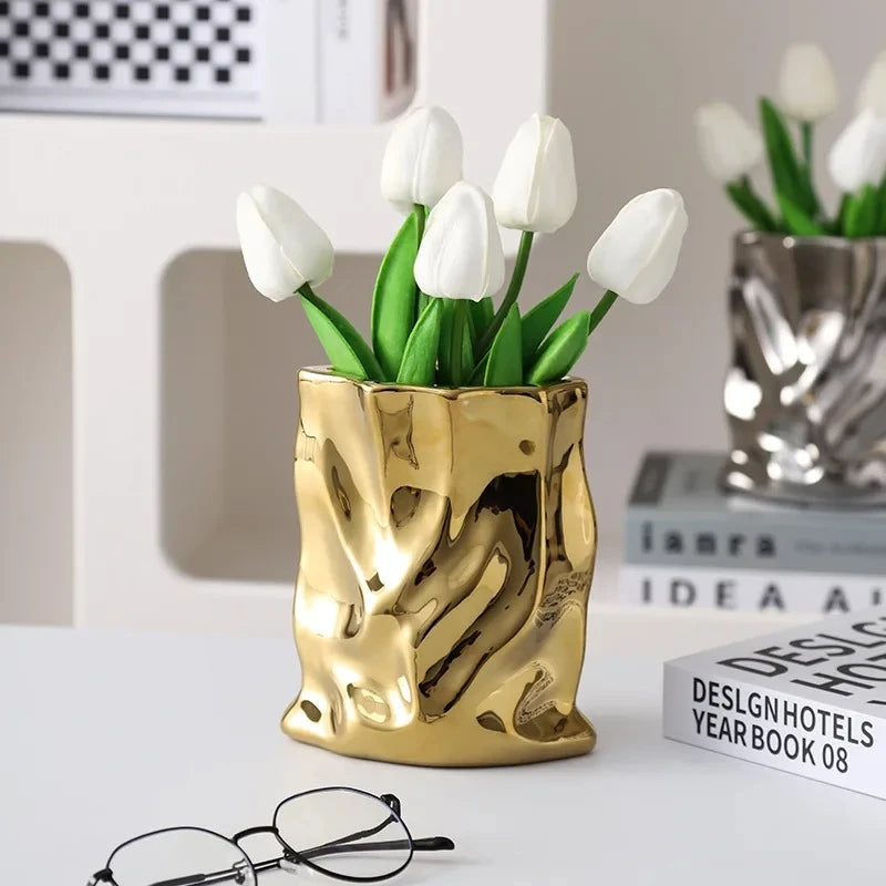 Gold vase with white tulips inside on a white surface