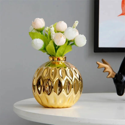 Gold Vase on a white table with flowers inside