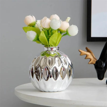 Silver vase on a white table with flowers inside