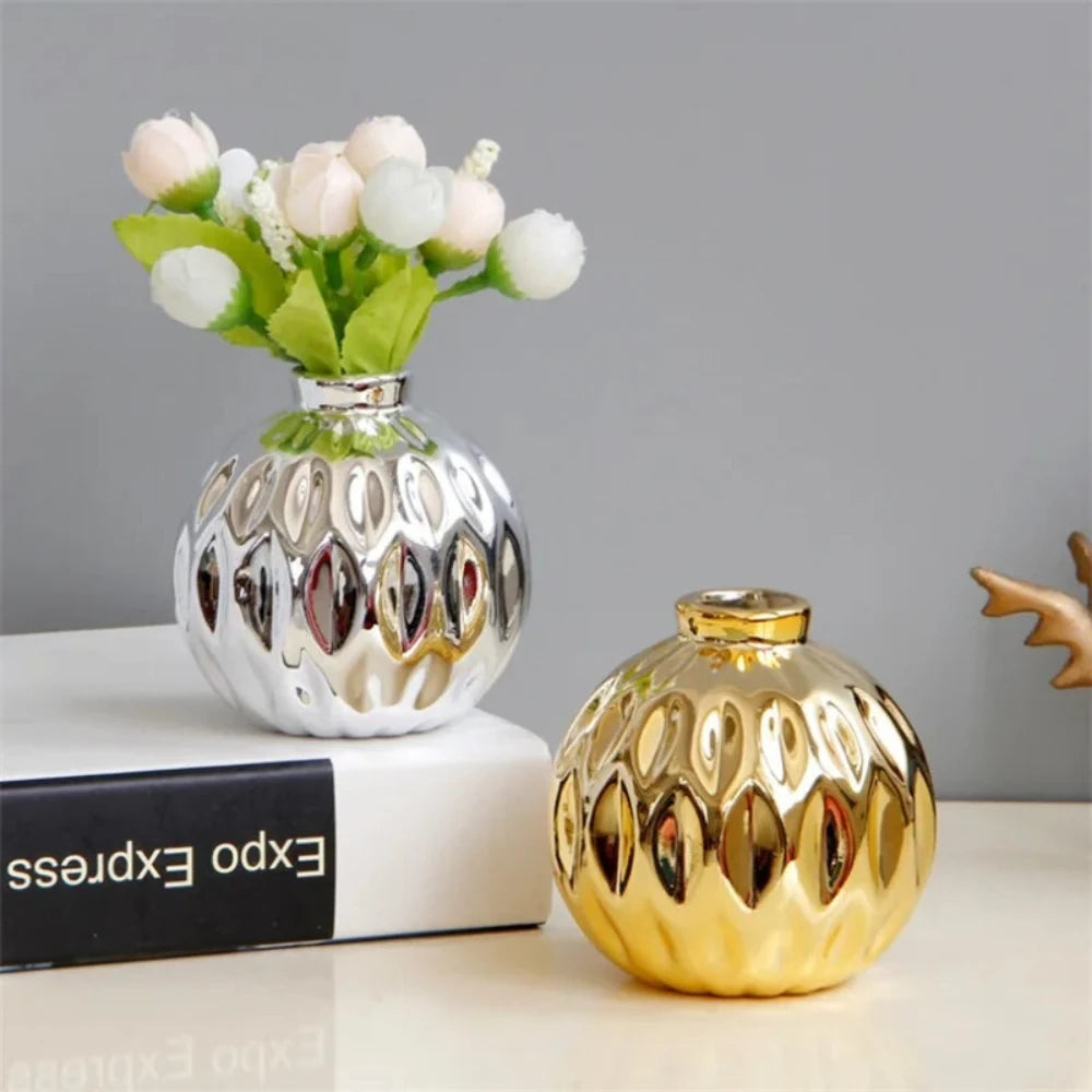 Gold and Silver Vases on a white table with flowers inside 