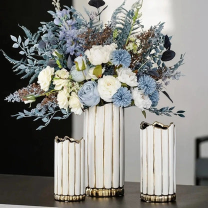 Three Gold and White Vases with blue flowers inside on a brown table