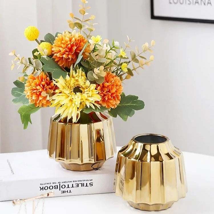 Two Golden Vases with flowers inside sitting on a book