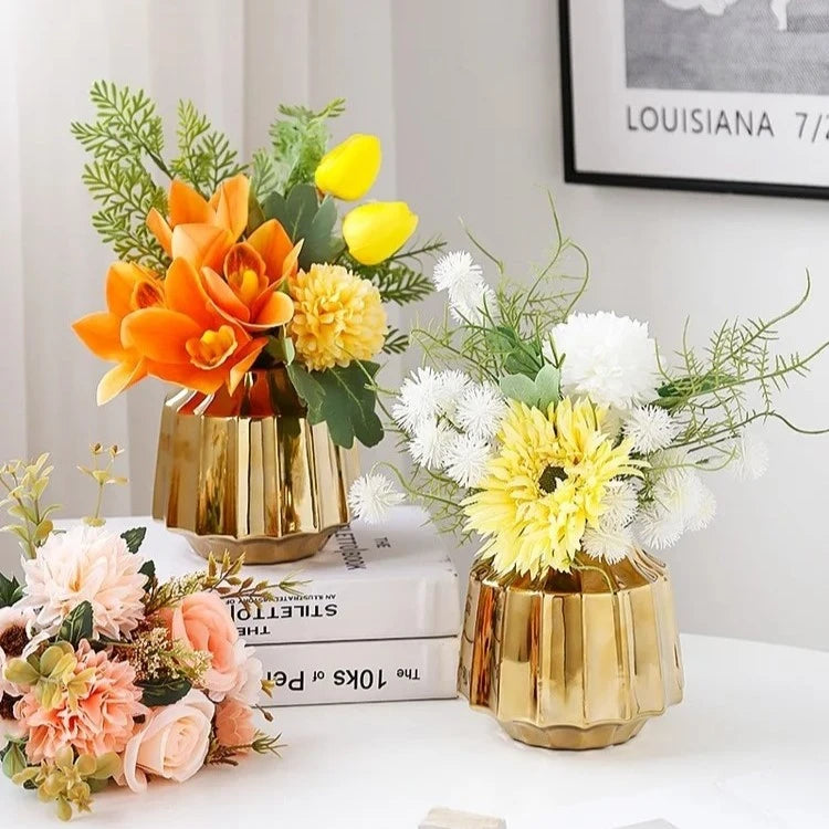 Two Golden Vases with flowers inside on a white surface