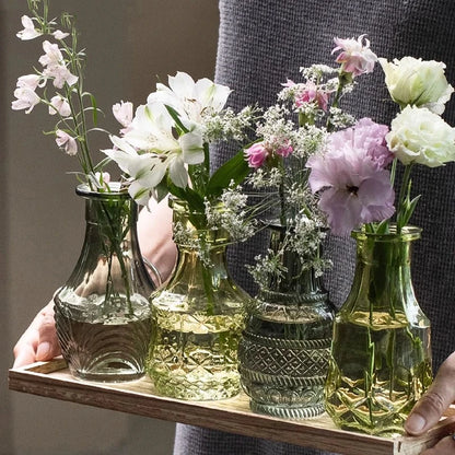 Person holding a wooden tray with Four Green Small Vase on it