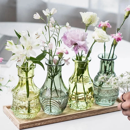 Four Green Small Vases with flowers inside on a wooden tray