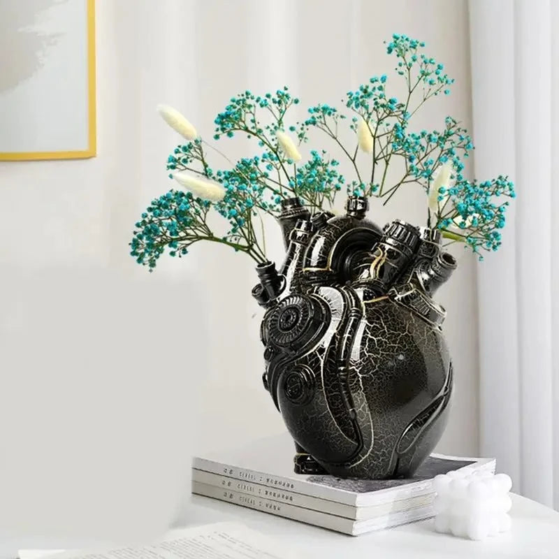 Heart Vase with cyan flowers inside standing on three books next to a candle