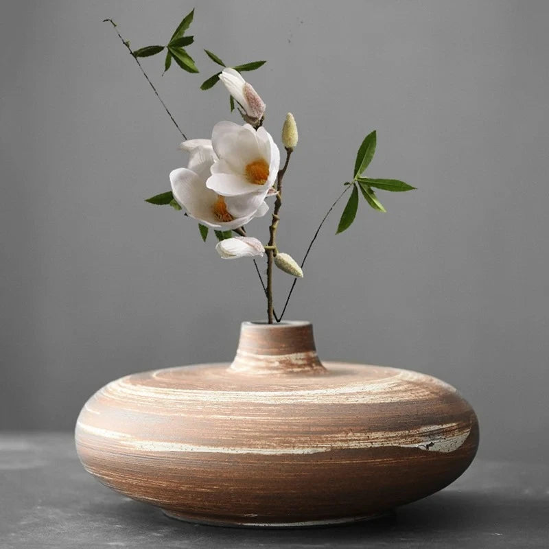 Japanese Vase in milky brown with white flowers inside on a gray surface