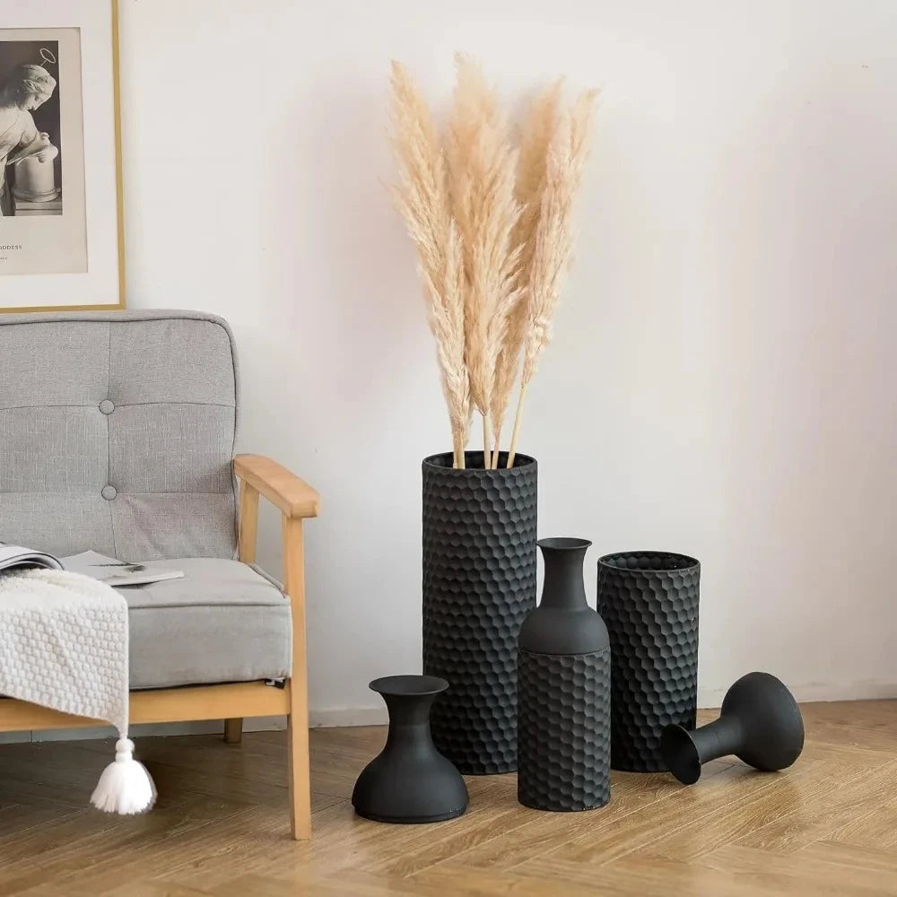 Large Black Vases next to a couch on a brown wooden surface