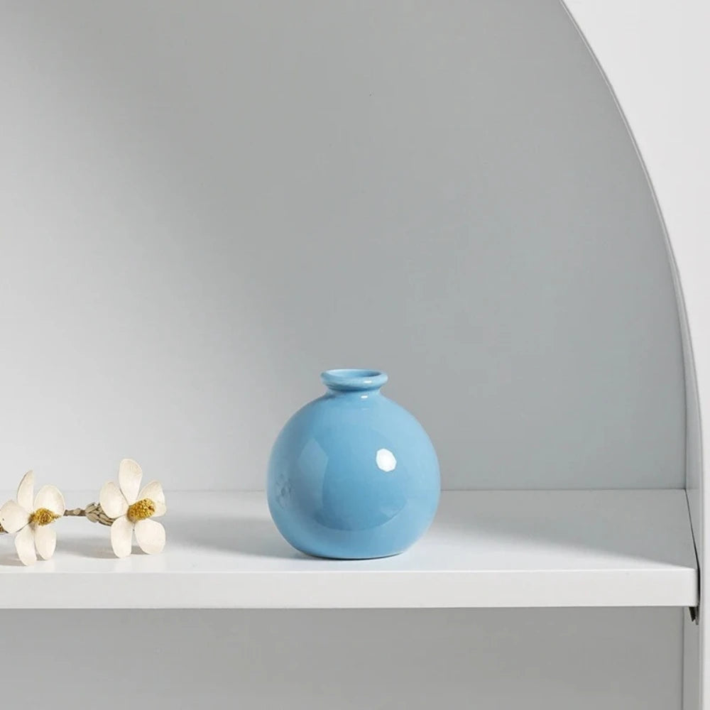 Light Blue Vase on a white shelf next to flowers