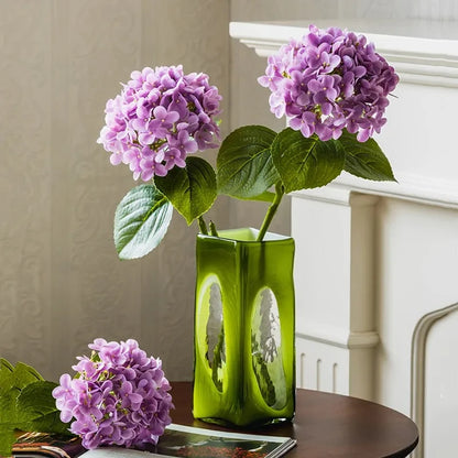 Lime Green Vase with purple flowers inside on a wooden table