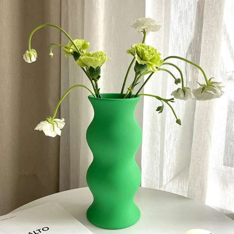 Matte Green Vase with flowers inside on a white table