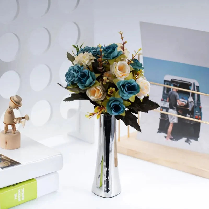 Metal Silver Vase on a white surface with blue and white flowers inside