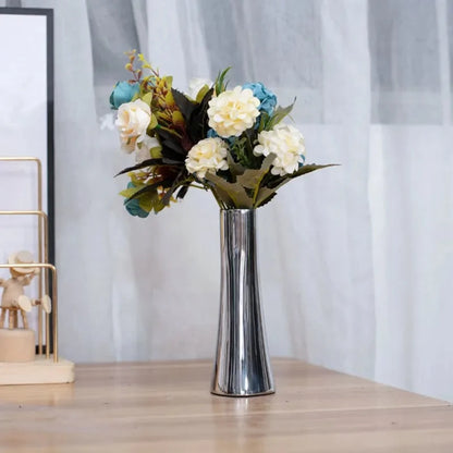 Metal Silver Vase with flowers inside on a beige table