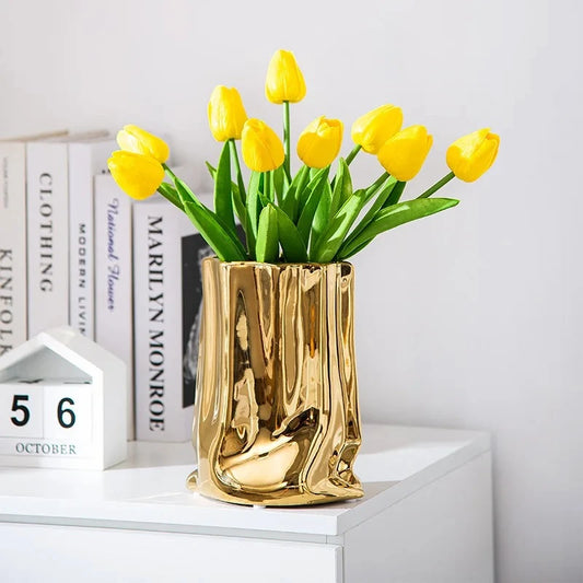 Metallic Gold Vase on a white shelf with yellow flowers inside