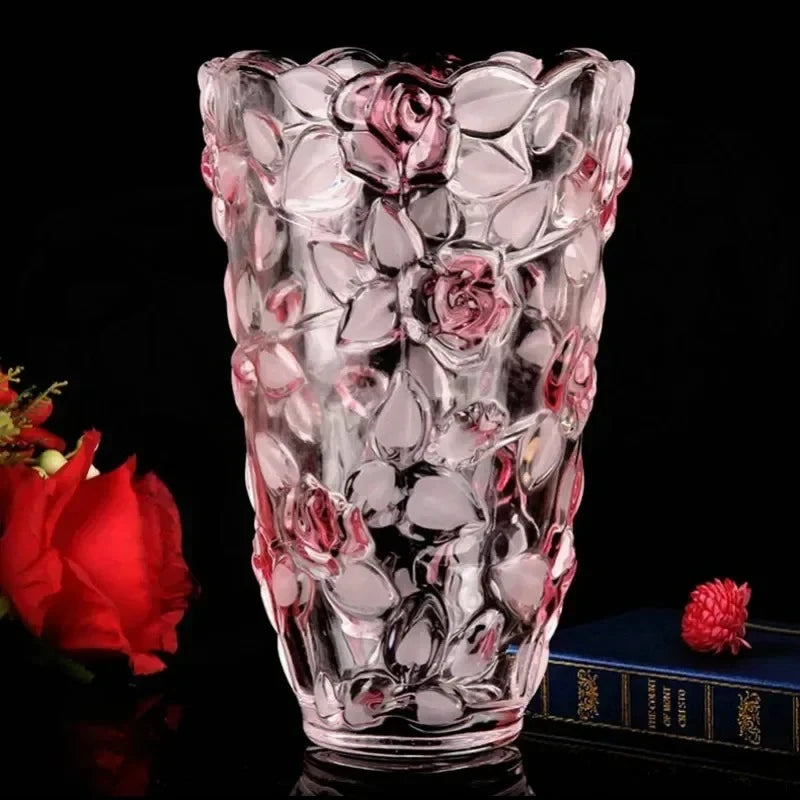 Pink Crystal Vase on a shiny black surface next to a red rose and a blue book