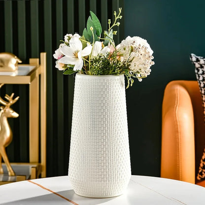 Plastic Cylinder Vase with flowers inside on a white table