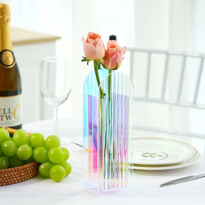 Plastic Vase with flowers inside standing on a table next to cutlery